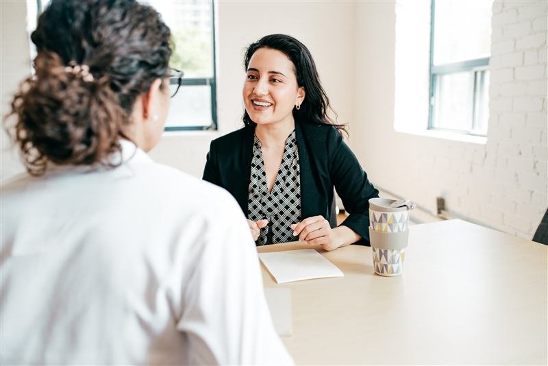 Two people in a calm, supportive one-on-one conversation at a table